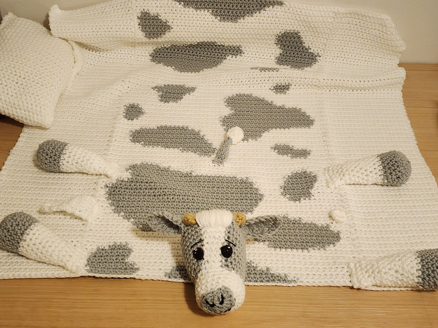 Full view of a handmade cow print baby blanket spread out for tummy time and floor play