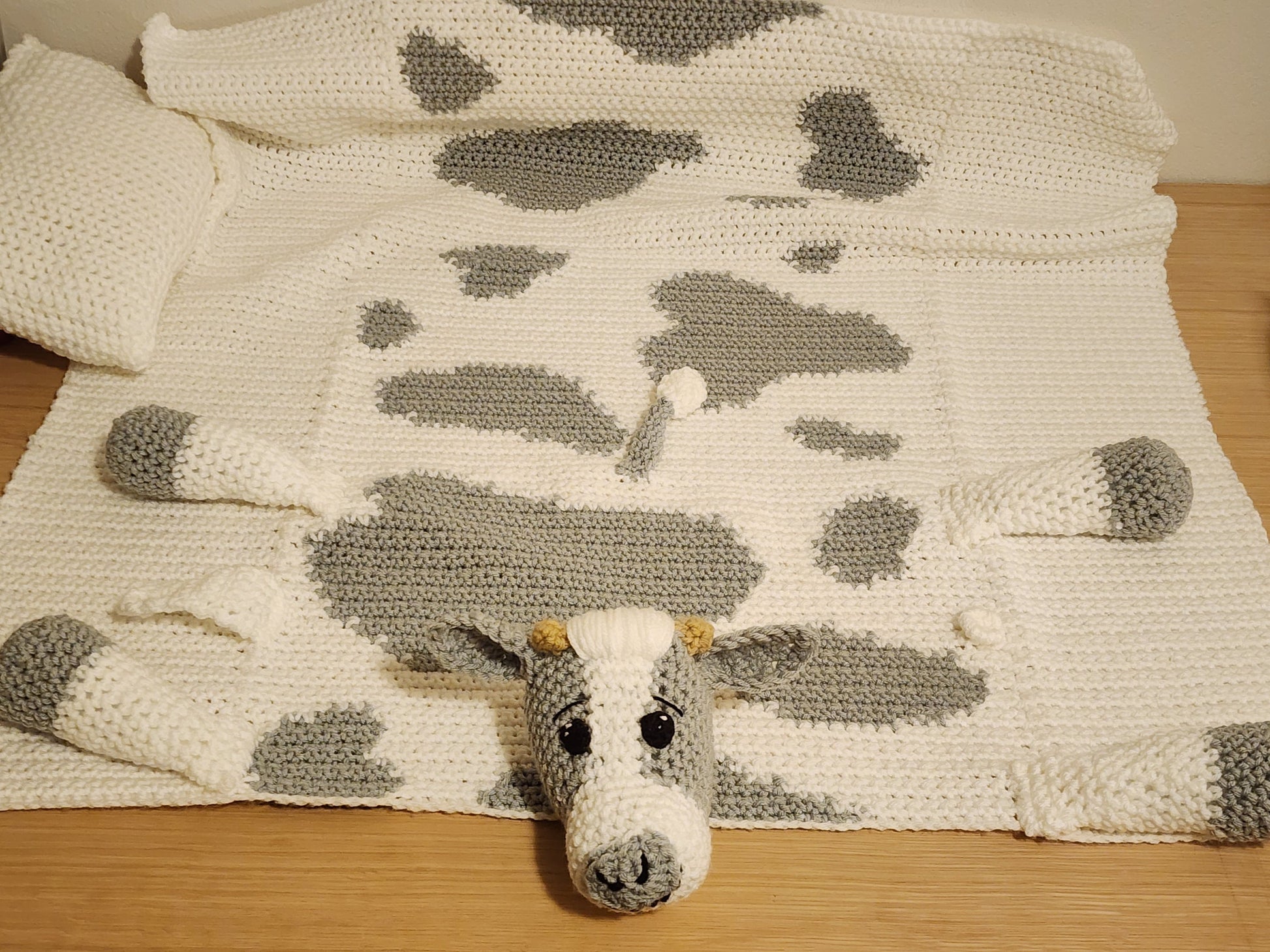 Full view of a handmade cow print baby blanket spread out for tummy time and floor play