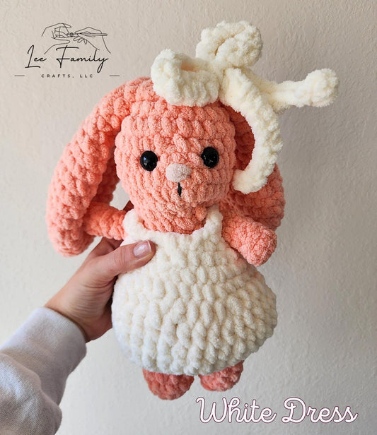 A pink crochet bunny with a white dress and white headband.