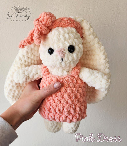 A white crochet bunny wearing a pink crocheted dress and pink headband with a bow.